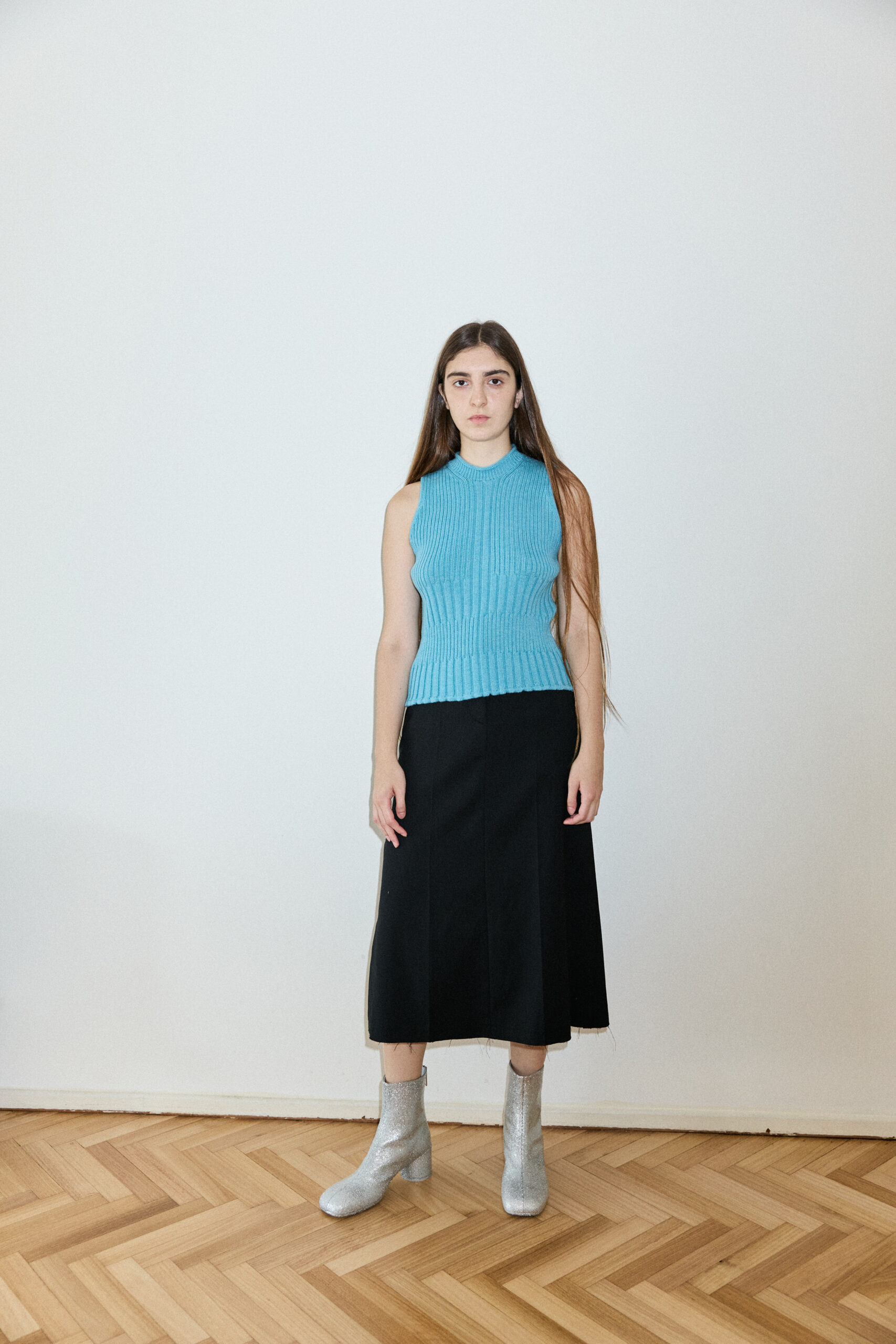 Model wearing the 9v9 blue ribbed tank top with black skirt, three-quarter length portrait
