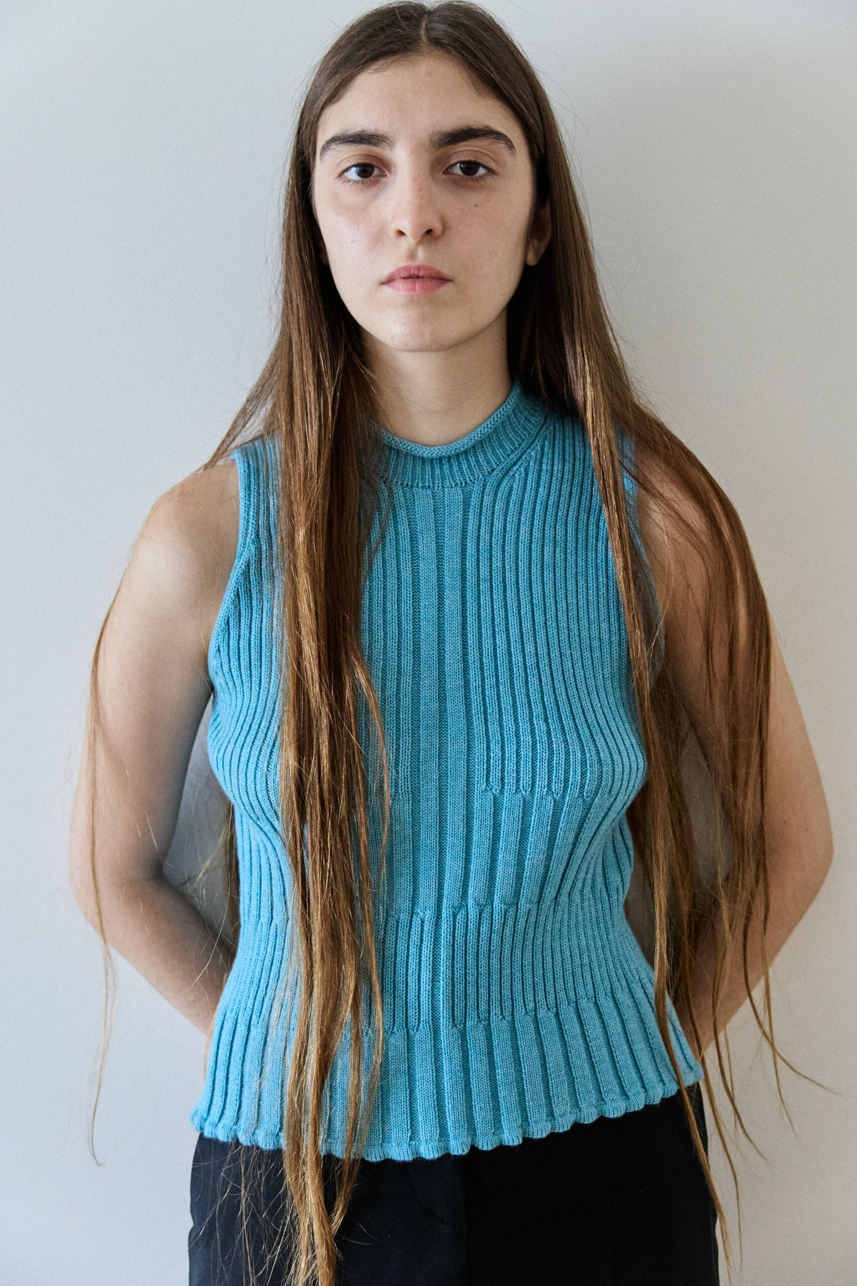 Model wearing the 9v9 blue ribbed sleeveless tank top in merino wool, front portrait, long straight hair